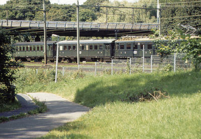 851673 Afbeelding van een historische trein die stilstaat onder het viaduct in de Waterlinieweg bij het Ravelijnpad te ...